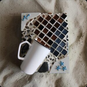 Hug in a Mug — mosaic artwork by Sarah Ramharrack, warm bronze and black tiles with white ceramic mug